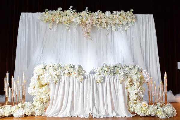 Elegante Brauttisch-Deko mit weißen Rosen, goldenen Kerzenhaltern und edler Tischwäsche